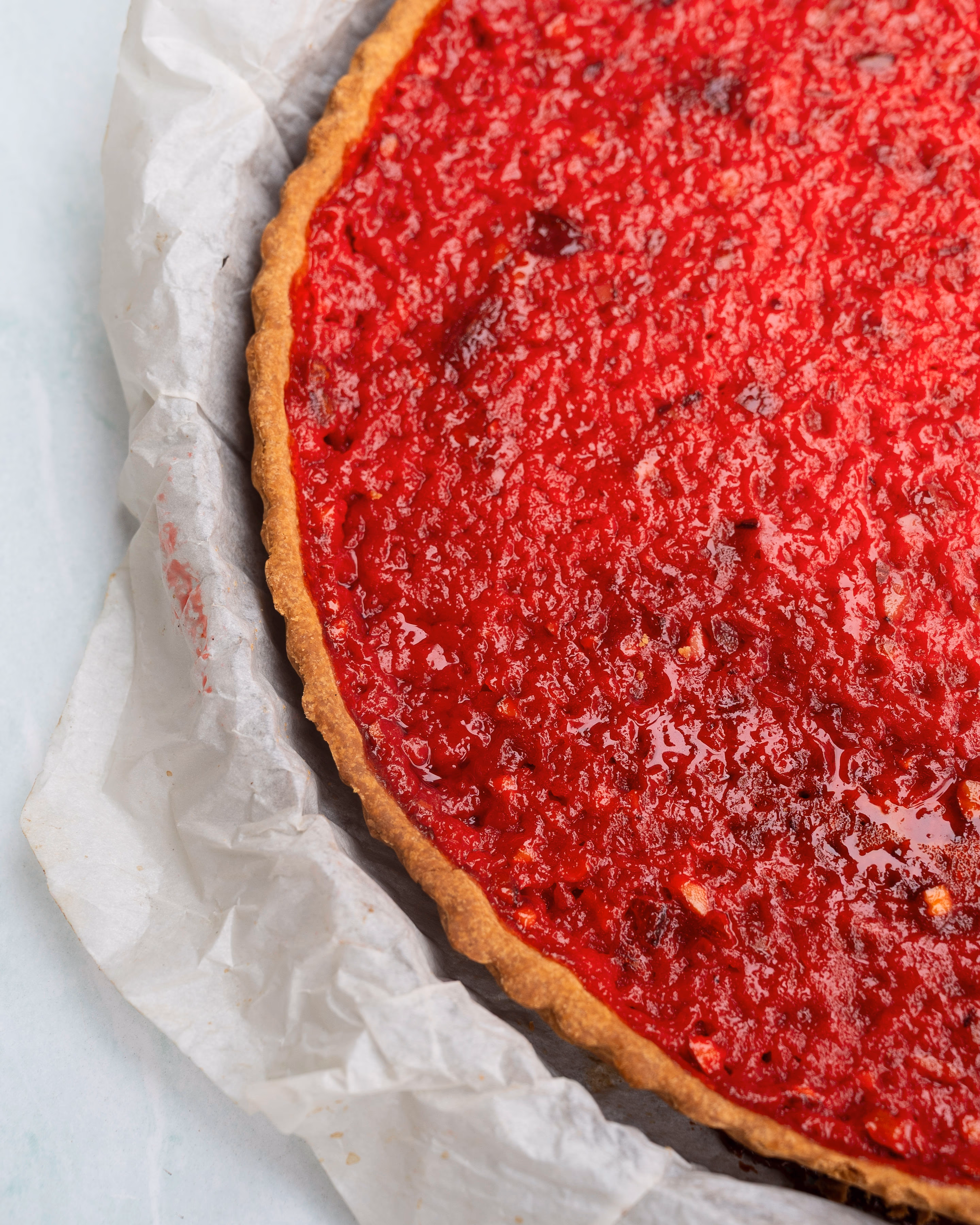 Tarte à la praline rose entière, appareil pris et brillant sur sa pâte dorée