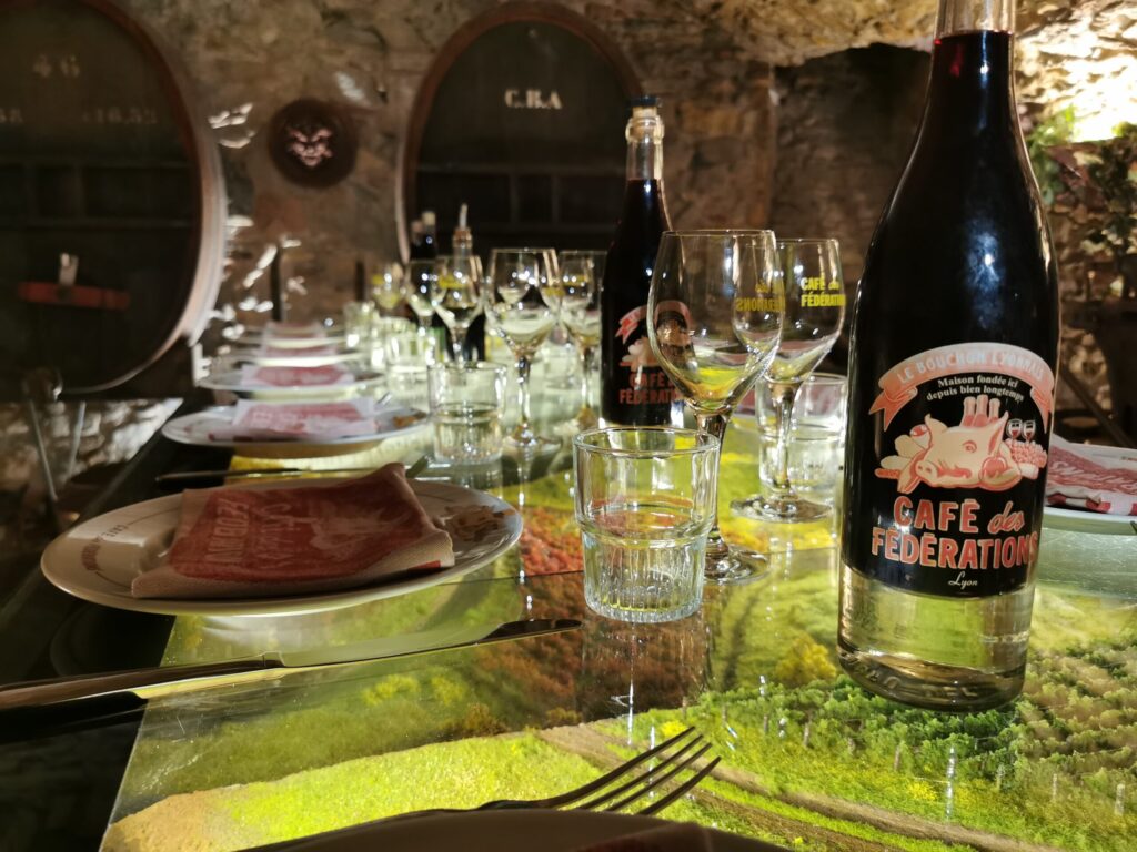 une table au café des fédérations avec les assiettes et les pots lyonnais de vin