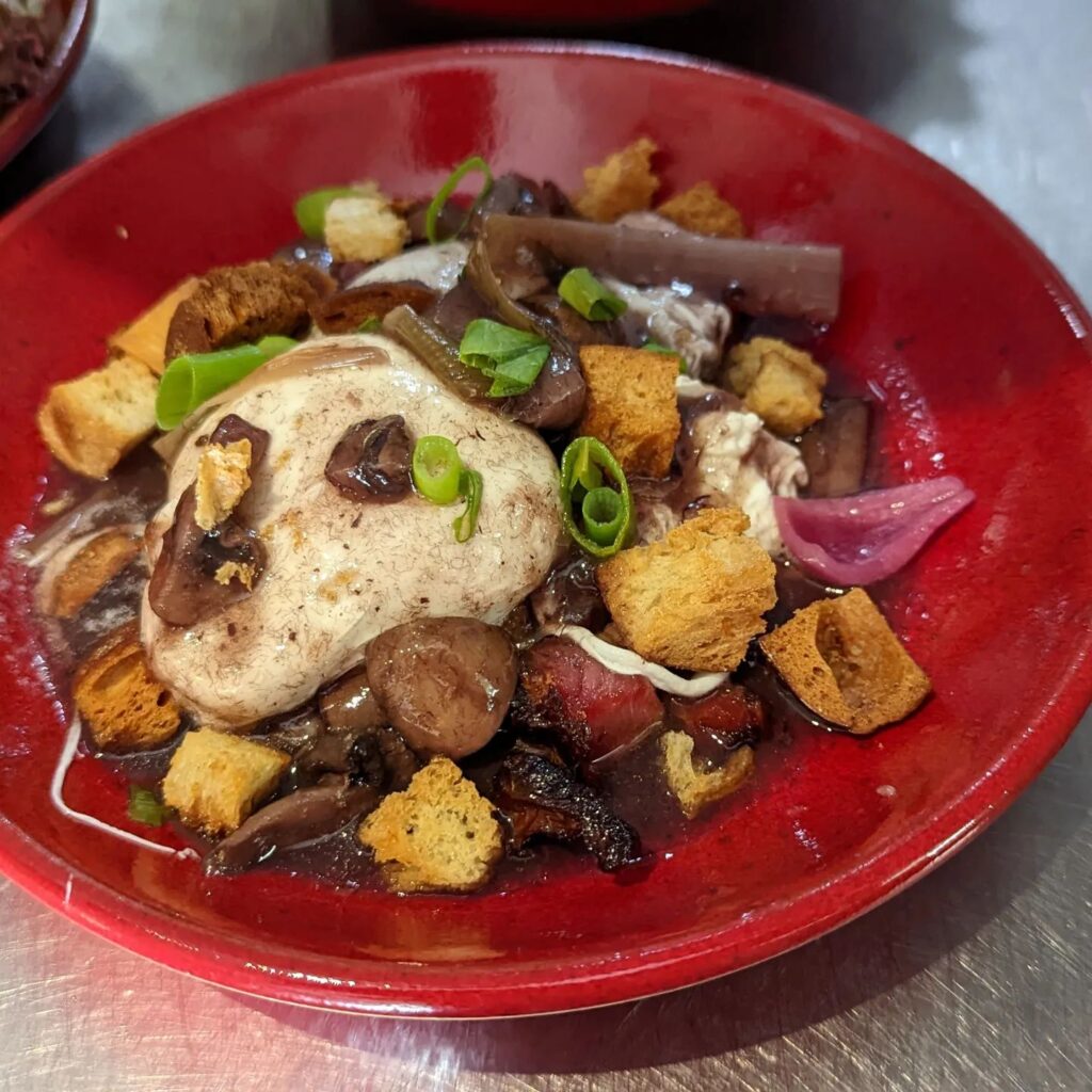 une assiette avec des oeufs en meurette, des champignons et des cebettes